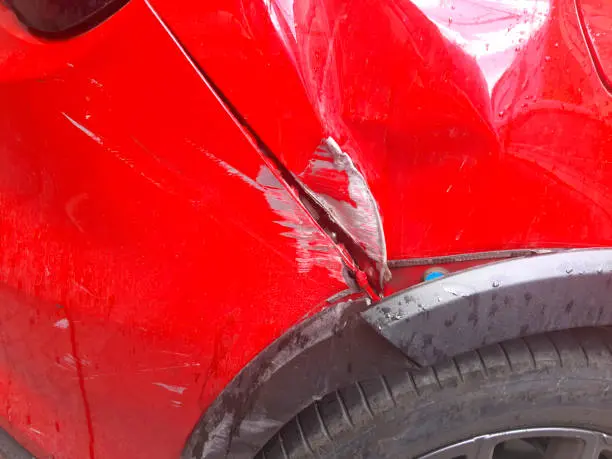 A red car with a visibly damaged front end, showcasing dents and scratches on the hood and bumper, can be fixed with our expert Bumper Repair Houston Texas services