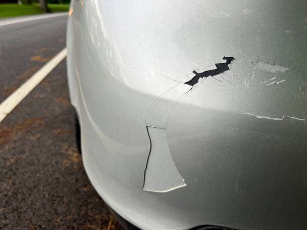 A vehicle with a visibly cracked windshield and a broken window showcasing the extent of its exterior damage emphasizes the need for plastic bumper repair