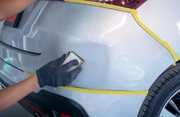 An individual engaged in painting the front of a car demonstrating creativity and precision in their work essential for effective plastic bumper repair