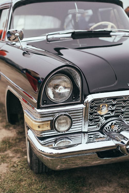 Detailed close-up of a classic car featuring its headlights on highlighting the vehicle's timeless elegance and craftsmanship ideal for those looking to restore chrome bumper