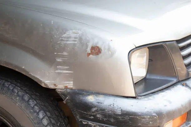 Close-up of a car's front bumper with noticeable rust, emphasizing the effects of weathering and age, making it a prime candidate for bumper reconditioning