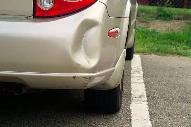 A car with a bumper sticker that says do not park like an asshole advocating for respectful parking practices while also needing a quick fix for bumper falling off