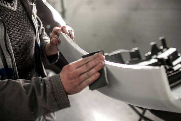 A man is focused on painting a car with a brush demonstrating skill and precision in his automotive project reflecting the attention needed to achieve the average bumper repair cost