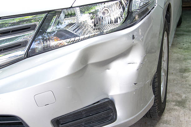 A damaged car parked inside a garage showcasing visible dents and scratches on its exterior which may impact the bumper repair cost