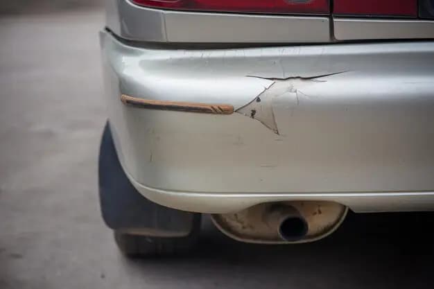  A vehicle displaying a broken bumper and a damaged tail light indicating significant exterior damage and the urgent need to repair cracked bumper cover