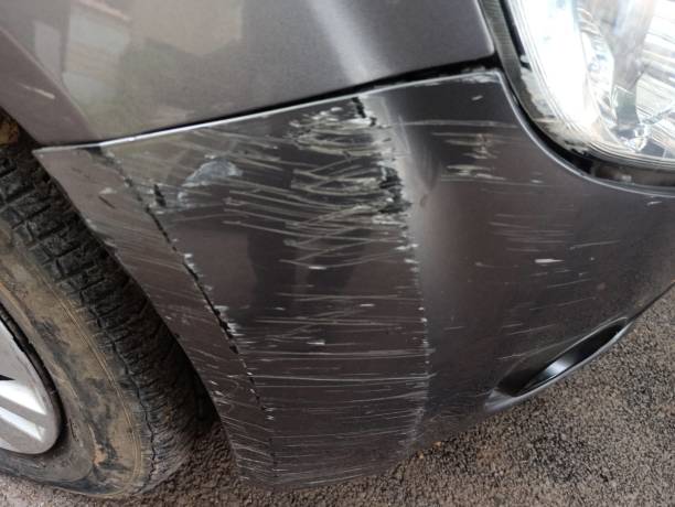 A vehicle displaying a damaged front bumper and a flat tire suggesting it has been involved in a mishap and may require services to remove bumper scuffs