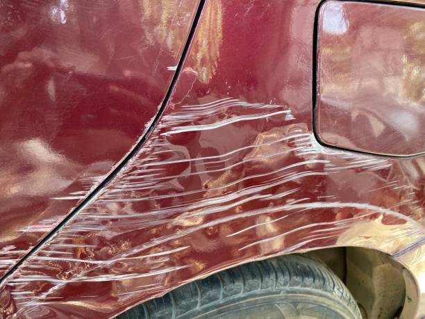 An automobile displaying a cracked windshield and a dented bumper indicating recent damage and the need to remove bumper scuffs