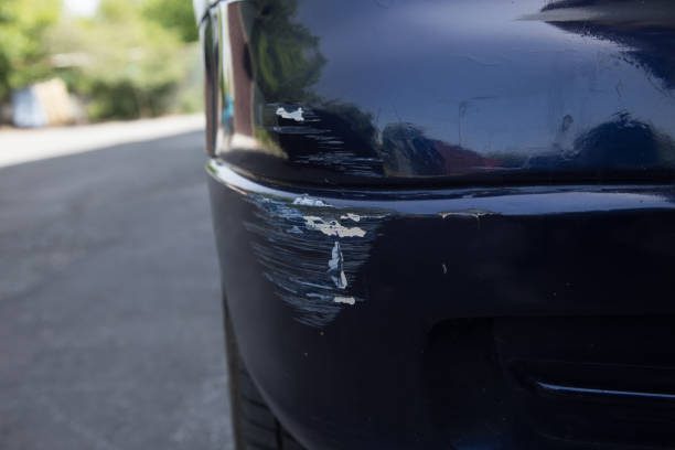 Close-up of a car's bumper showing significant damage with visible scratches and dents highlighting the need for small bumper crack repair after an impact or collision