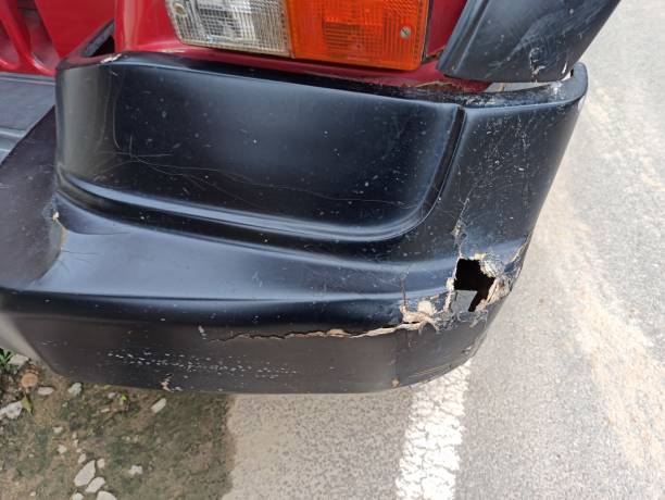 Rear view of a red Jeep with a visibly damaged bumper featuring dents and scratches in need of car bumper hole repair