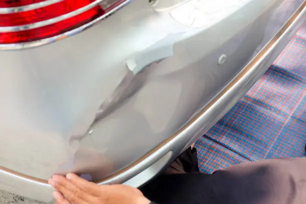 A man works on a car, concentrating on the damaged bumper, highlighting his dedication to vehicle maintenance, repair, and expert bumper reconditioning